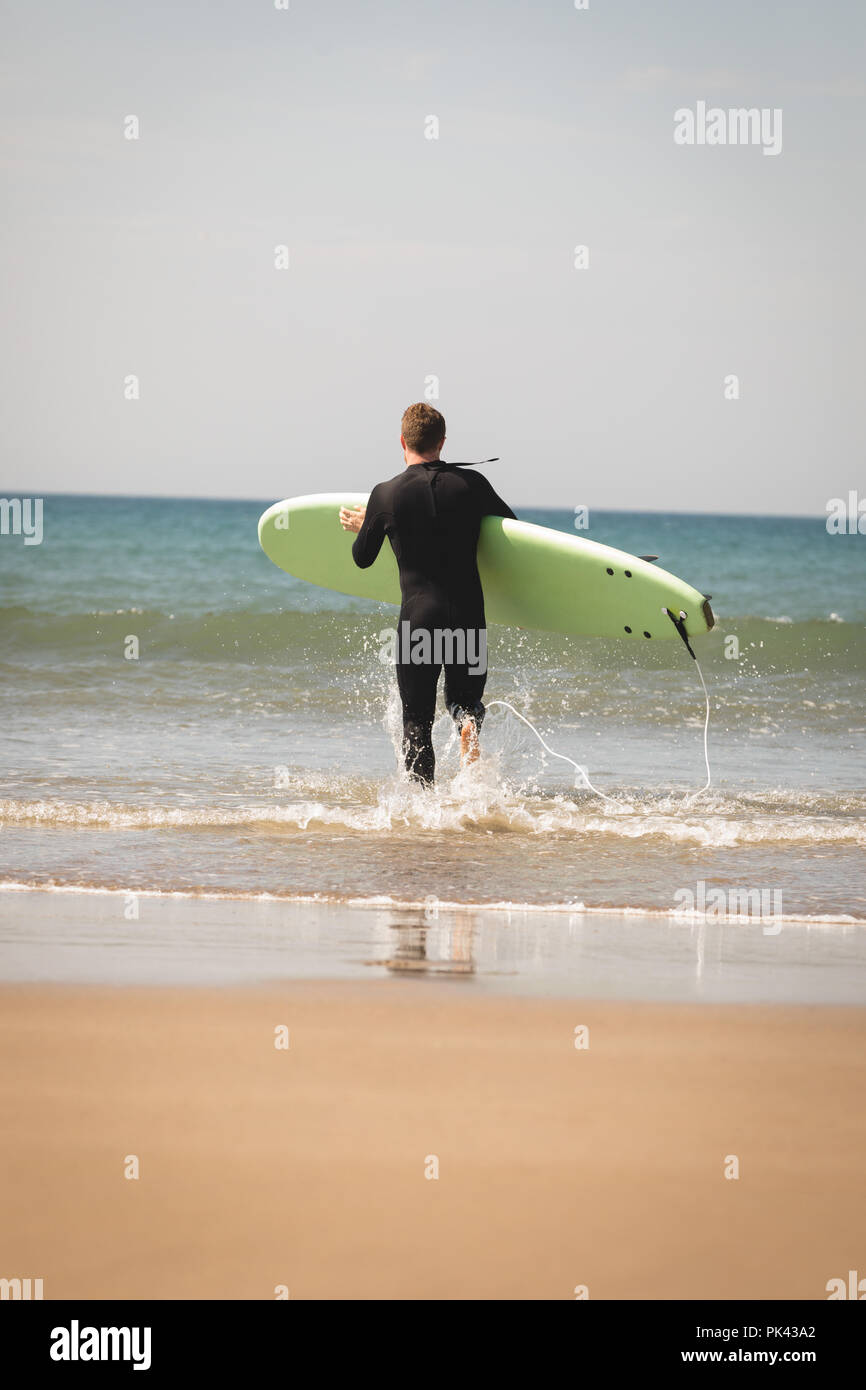 Surfer mit Surfbrett in Richtung Strand läuft Stockfoto