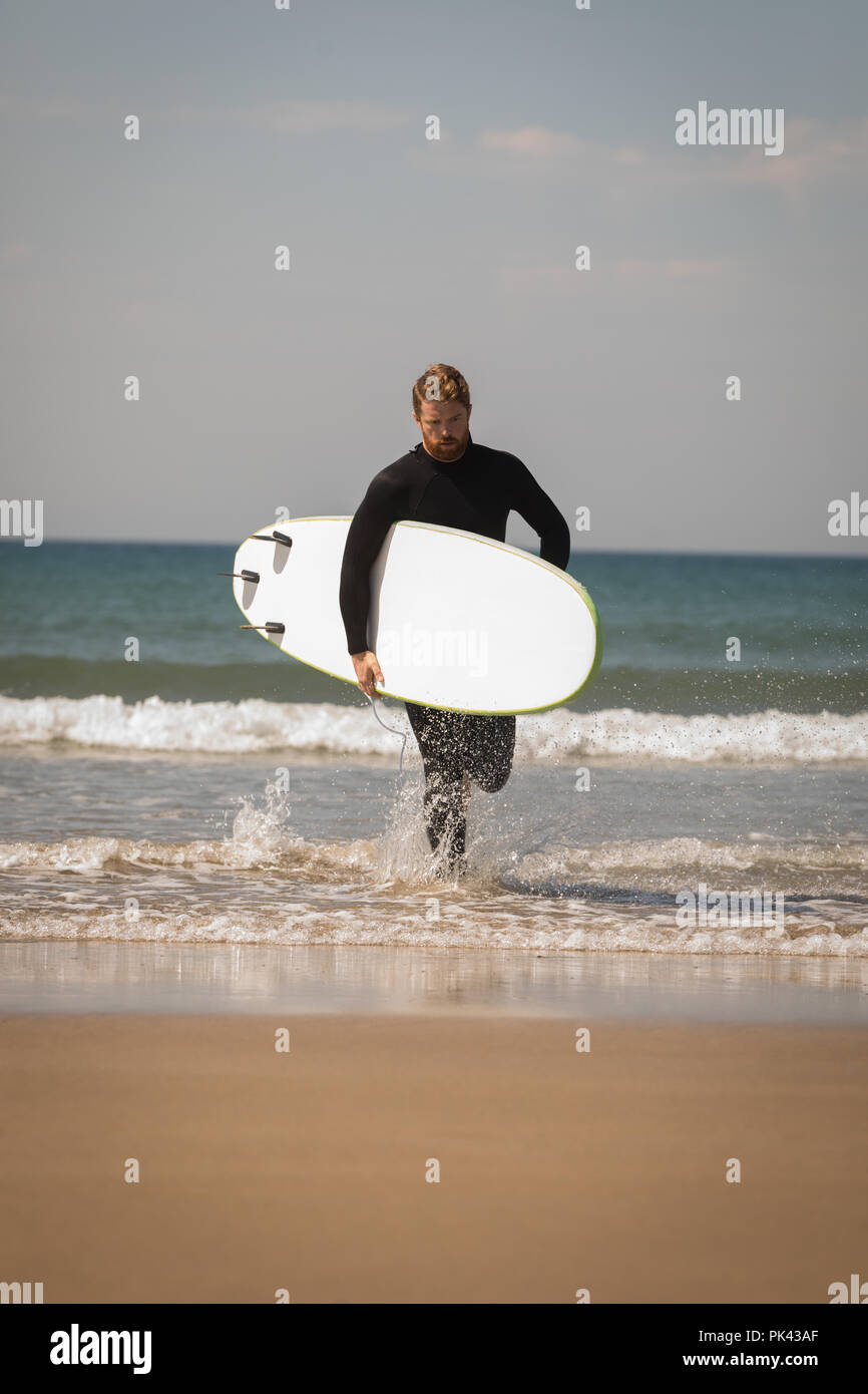 Surfer mit Surfbrett laufen am Strand Stockfoto
