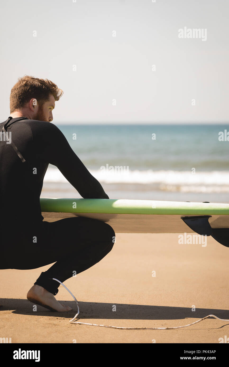 Surfer mit Surfbrett am Strand sitzen Stockfoto