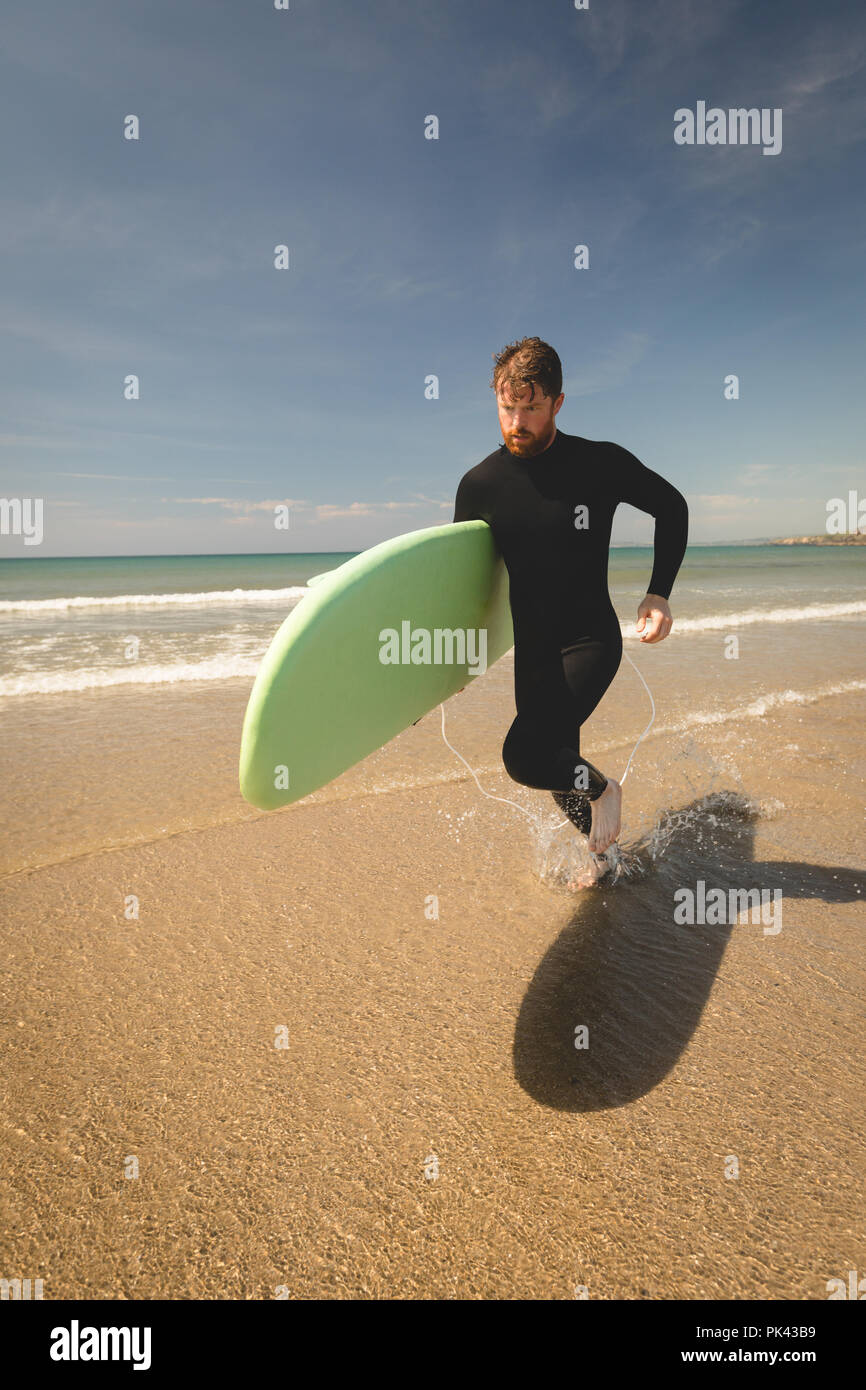 Surfer mit Surfbrett laufen am Strand Stockfoto