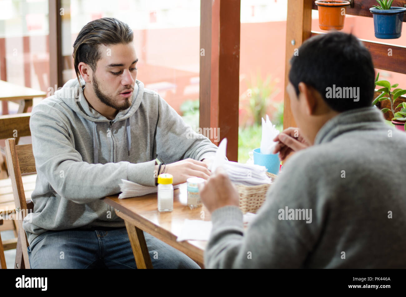 Gut aussehende junge Menschen zur Festsetzung der Tabelle mit Servietten, bevor die Gäste kommen Stockfoto