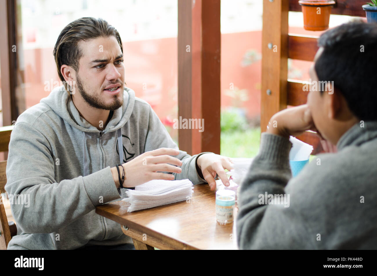 Gut aussehende junge Menschen zur Festsetzung der Tabelle mit Servietten, bevor die Gäste kommen Stockfoto
