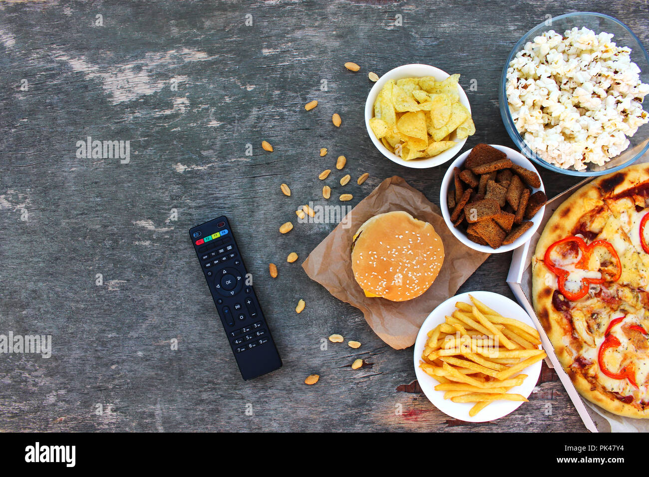 TV-Fernbedienung, Fast Food auf alten Holz- Hintergrund. Konzept der Junk-Essen. Ansicht von oben. Flach. Stockfoto