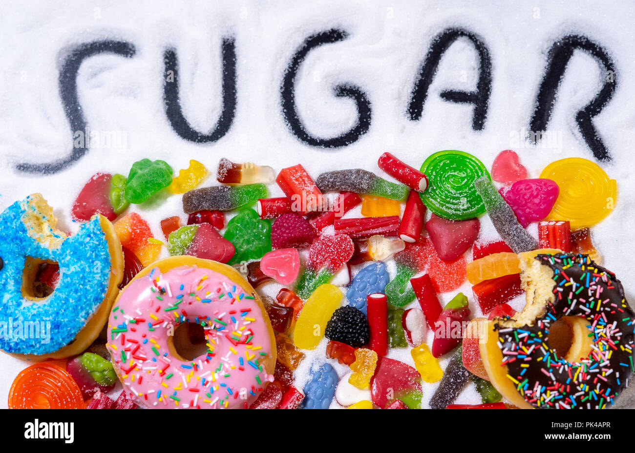 Mix von verführerischen Kuchen, Donuts und Bonbons mit Zucker ausbreiten und geschriebenen Text in ungesunde Ernährung, Schokolade Missbrauch Zucker Konzept, Körper Stockfoto