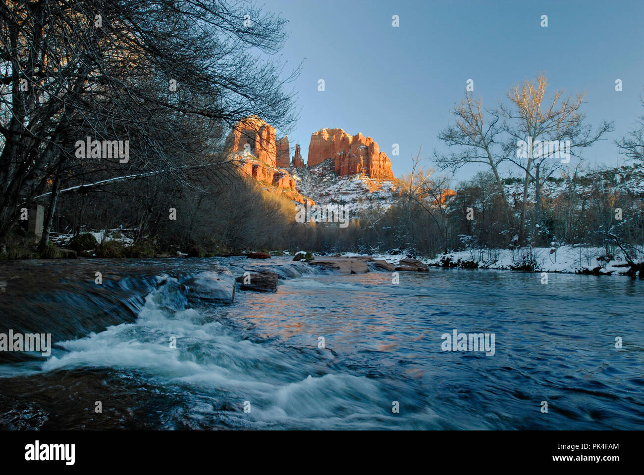 Winter Szene mit der sonnendurchfluteten Cathedral Rock Formation und der fliessende Gewässer des Oak Creek im Red Rock Crossing, südwestlich von Sedona, Arizona. Stockfoto