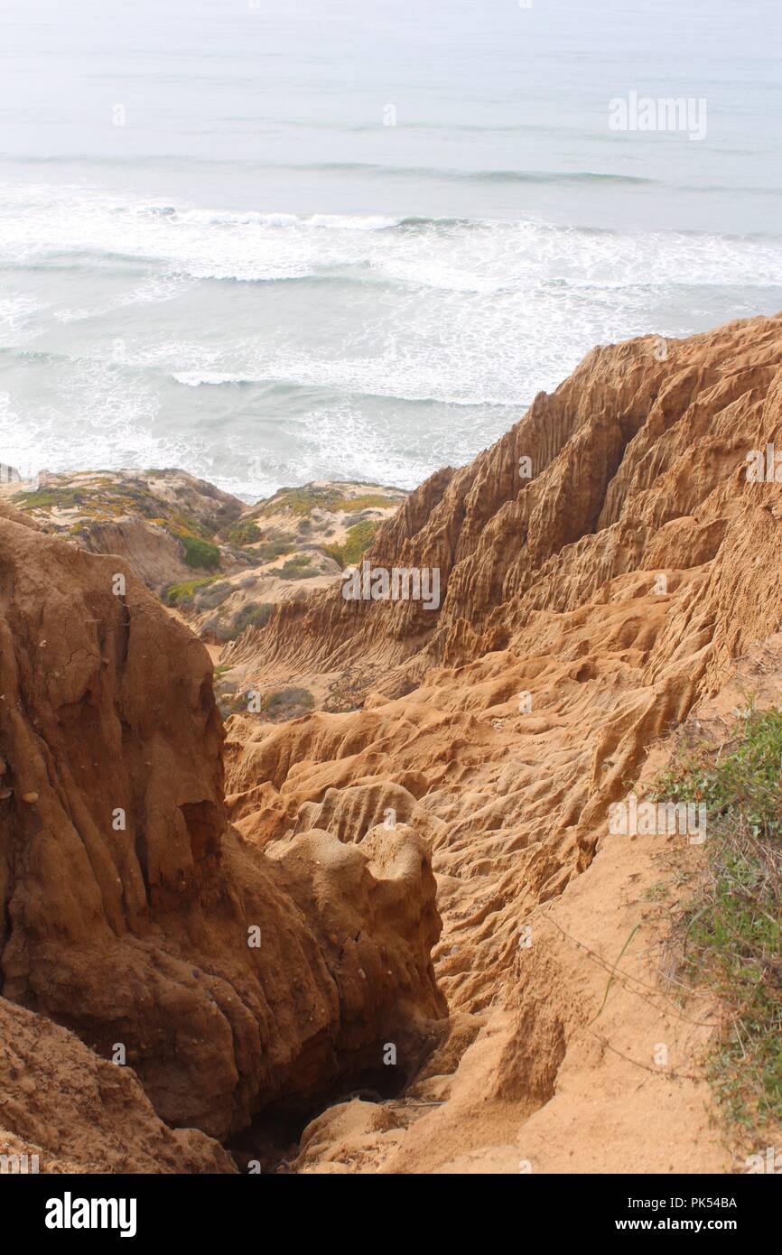 Oceanside tief orange Klippen im Vordergrund entlang der Strand von Torrey Pines State Preserve, San Diego, CA Stockfoto