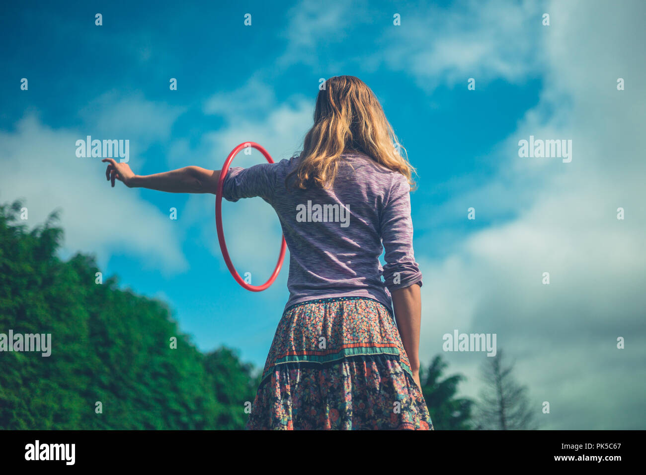 Eine junge Frau dreht sich ein Hula Hoop im Freien im Sommer Stockfoto