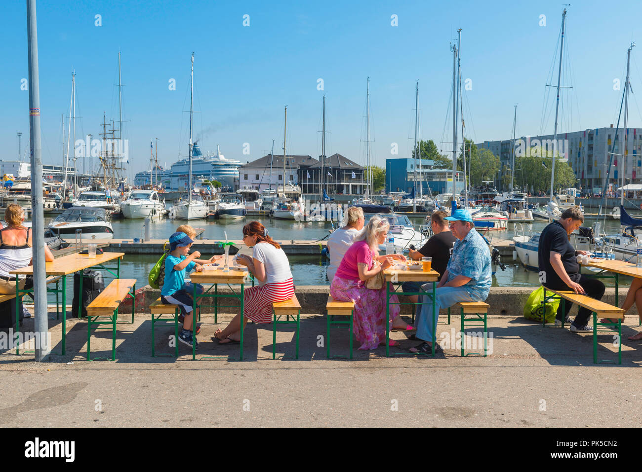 Leute, die im Sommer essen, sehen die Leute an einem Sommernachmittag, die am Tisch auf dem Kalamaja Sonntagsmarkt im Hafen von Tallinn, Estland, zu Mittag essen. Stockfoto