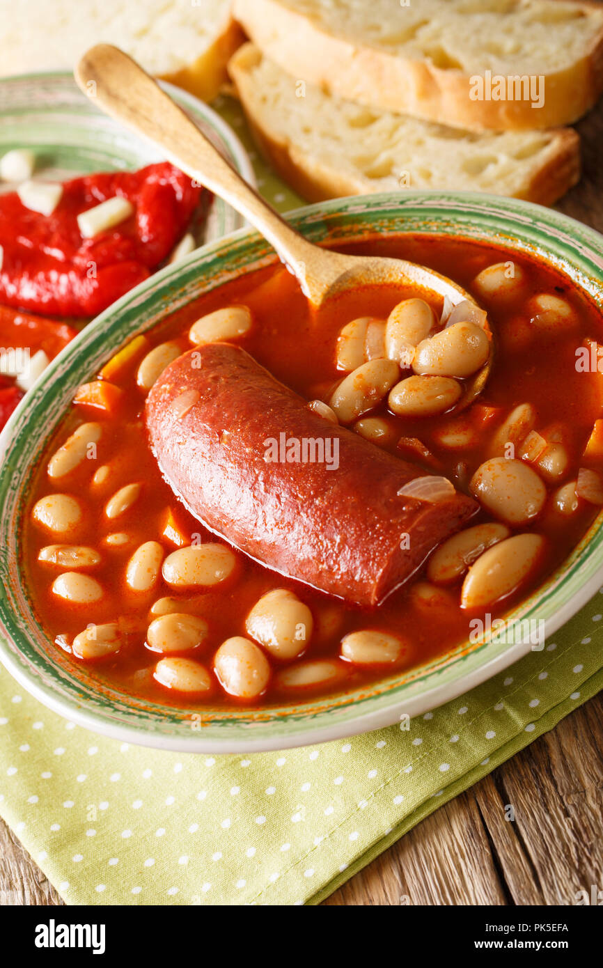 Balkan Essen pasulj Suppe mit Wurst mit eingelegten Pfeffer und Knoblauch in der Nähe serviert - auf den Tisch. Vertikale Stockfoto