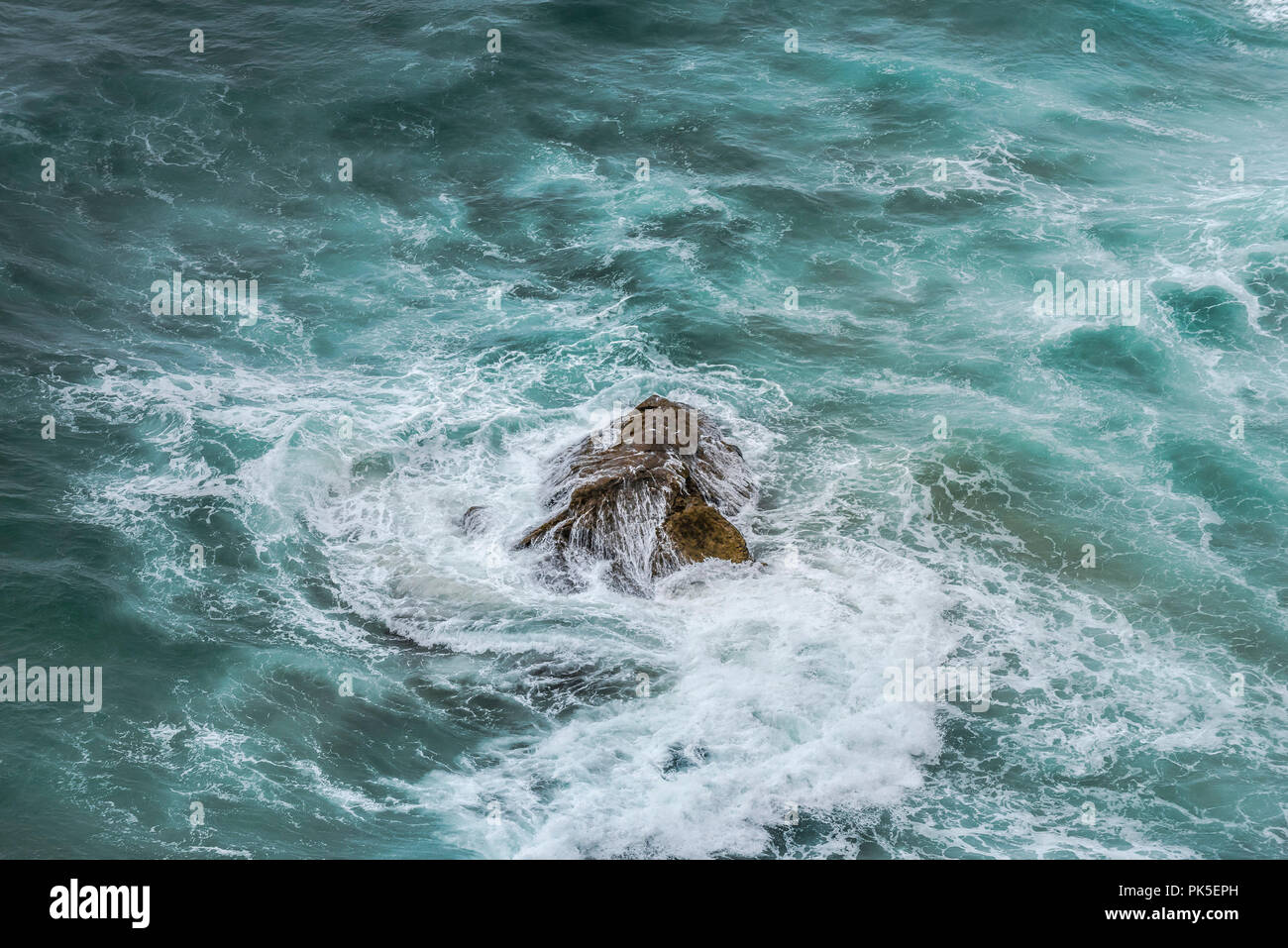 Ein Felsen in einem abgehackt wirbelnden Meer. Stockfoto