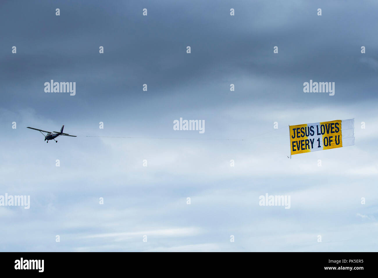 Ein kleines Flugzeug abschleppen ein Banner mit einer religiösen Botschaft. Stockfoto