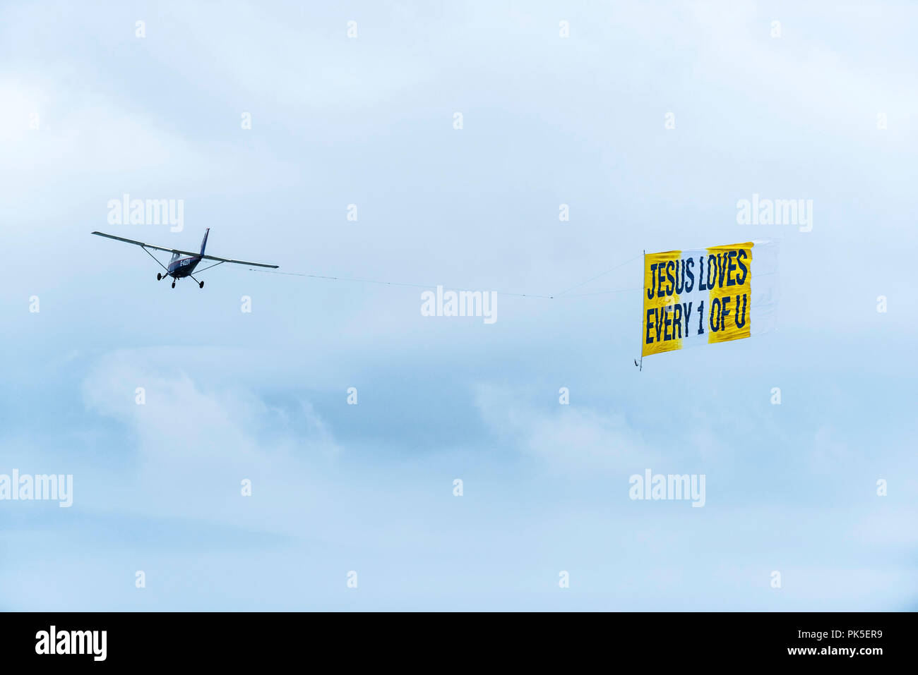 Ein kleines Flugzeug abschleppen ein Banner mit einer religiösen Botschaft. Stockfoto