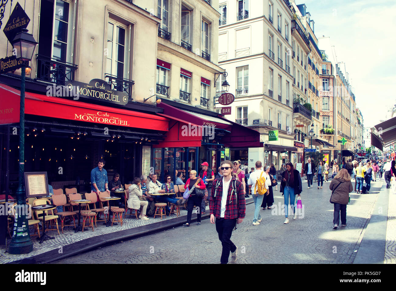 Menschen gehen auf der berühmten Rue Mouffetard Straße in Paris. Ein traditionelles Café/Bistro Ort ist im Hintergrund. Stockfoto