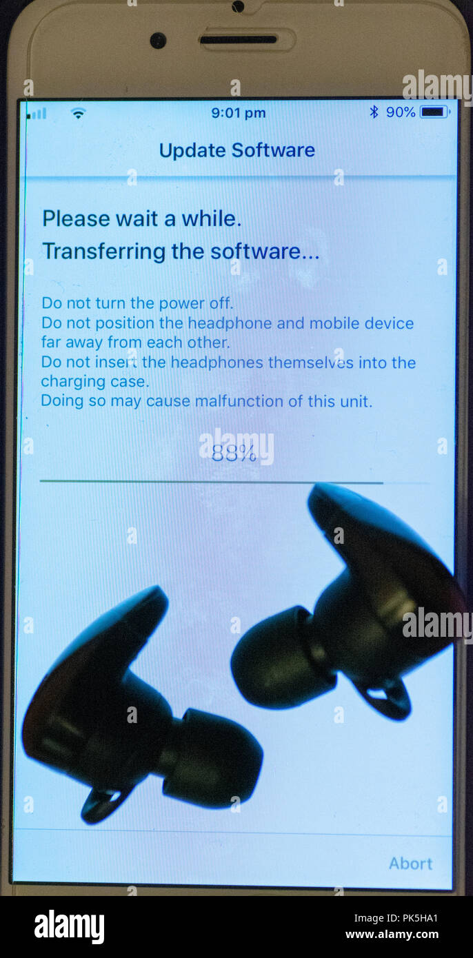 Drahtlose Ohrhörer, die eine Software von einem Mobiltelefon aktualisieren Stockfoto