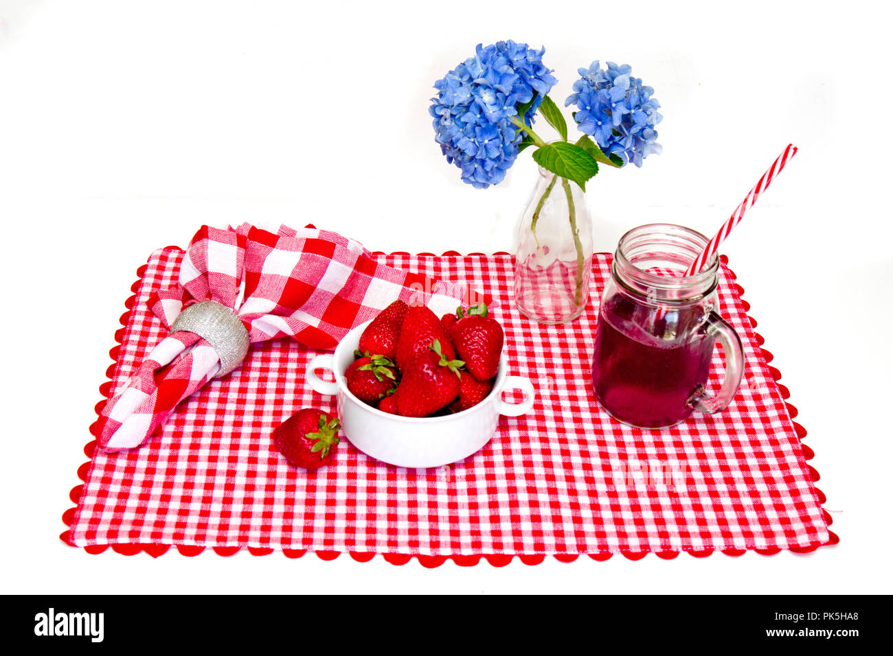 Patriotische, Rot, Weiß und Blau, Tisch mit Tischset, Schüssel mit Erdbeeren, Getränke im Glas mug und blaue Blumen in der Vase. Stockfoto