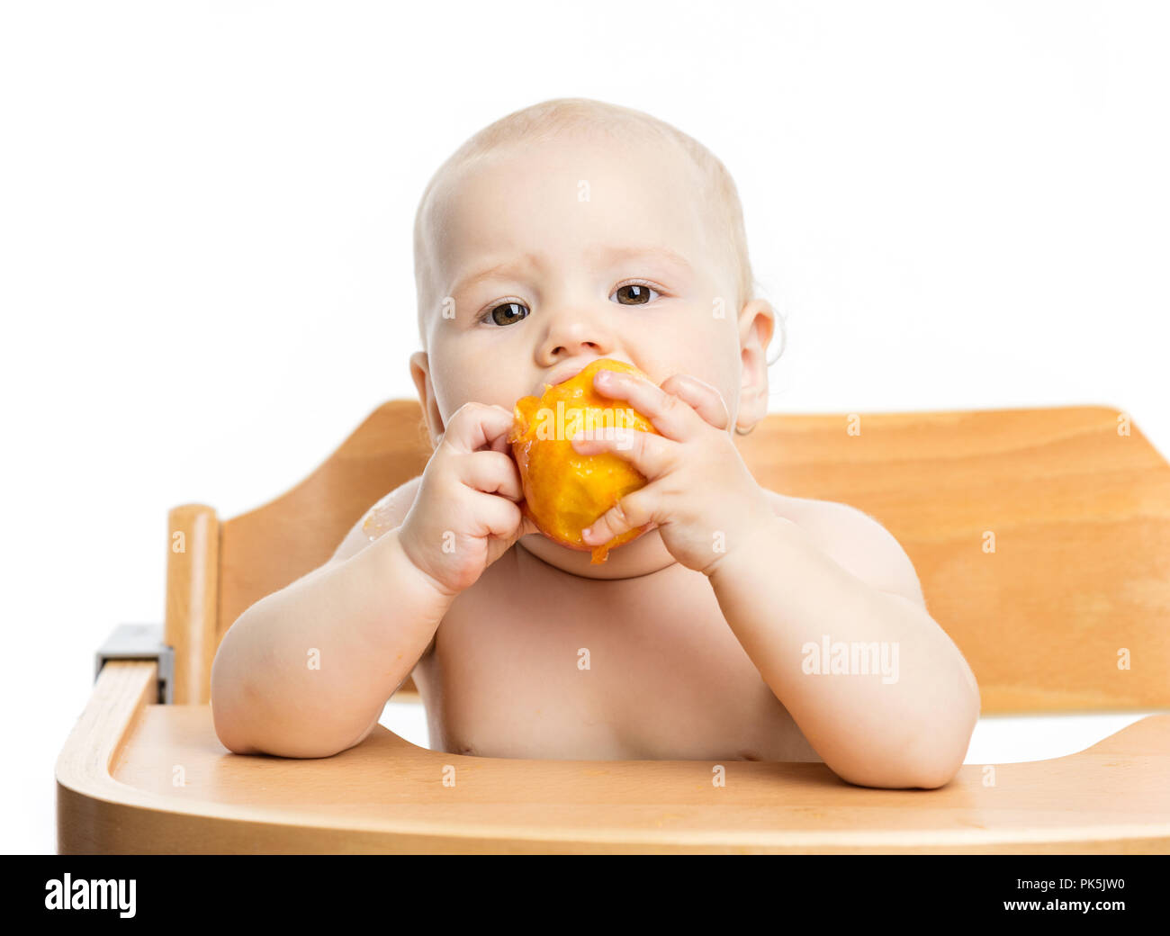 Cute Baby girl peach Essen während der Sitzung in hoher Stuhl über Weiß Stockfoto