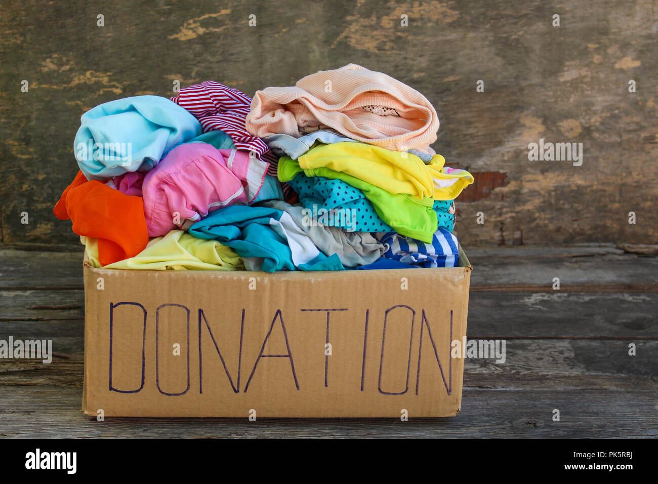 Spendenbox mit Kleidung auf dem alten Holz- Hintergrund. Stockfoto