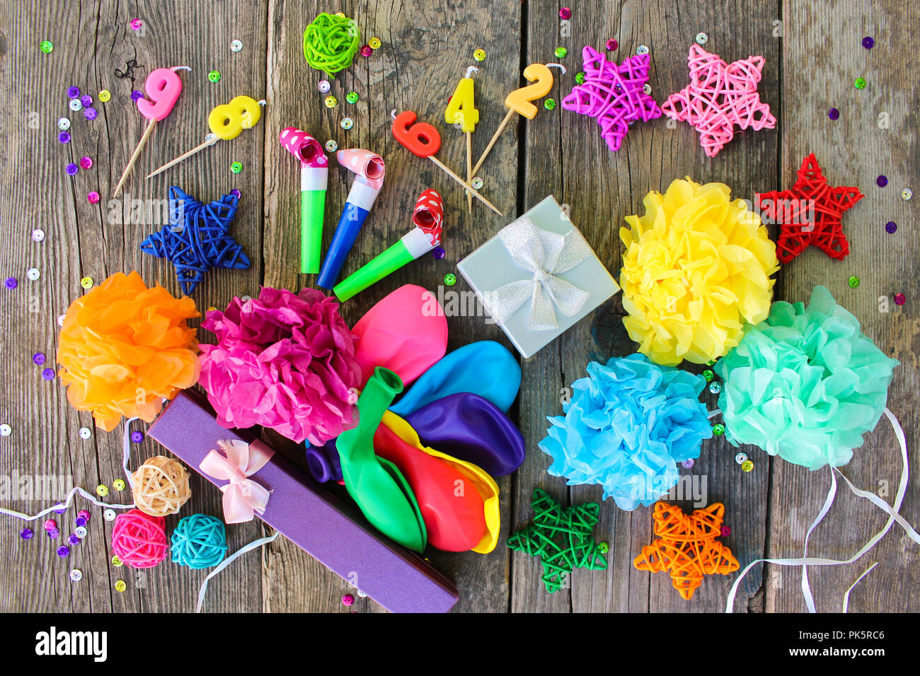 Pfeifen, Ballons, Geschenke, Kerzen, Dekoration auf alten hölzernen Hintergrund. Konzept der Kindergeburtstag. Ansicht von oben, flach. Stockfoto