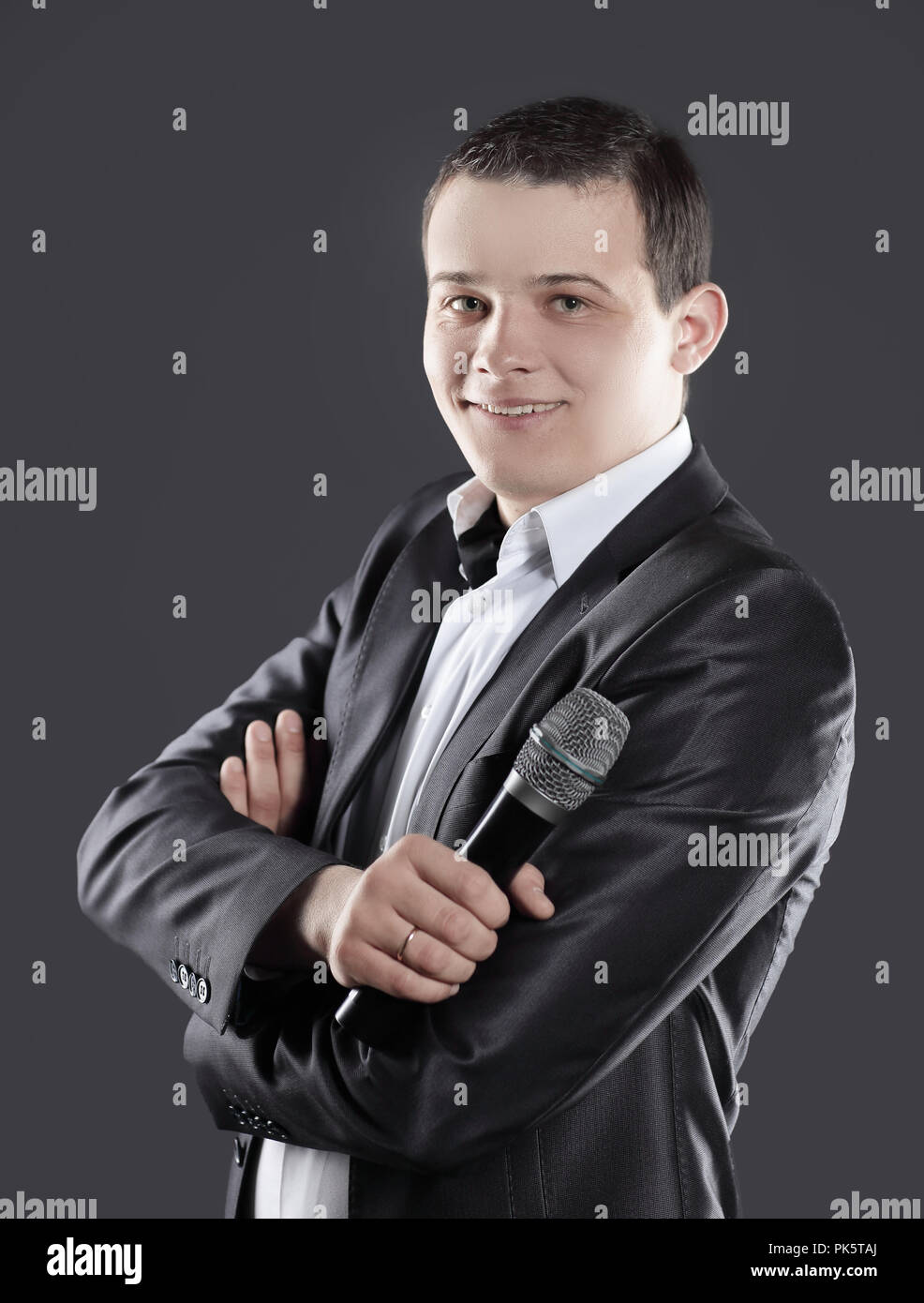 Zuversichtlich, dass junge Unternehmer mit Mikrofon auf schwarzem Hintergrund Stockfoto