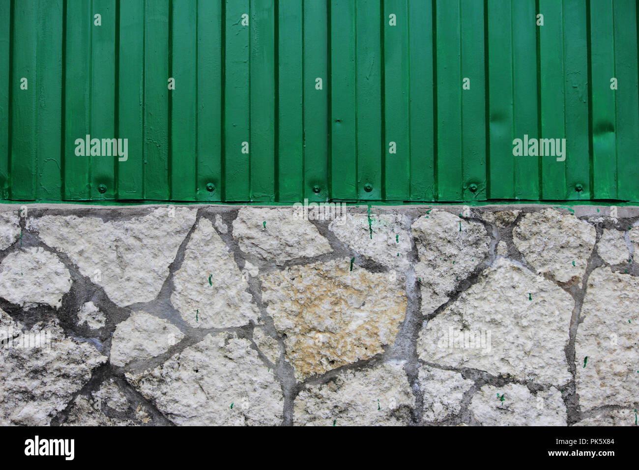 Die Mauer des Gebäudes wird von einem saftigen Grün metall Abstellgleis und endet in der Form von Stücken von Steinplatten. Stockfoto