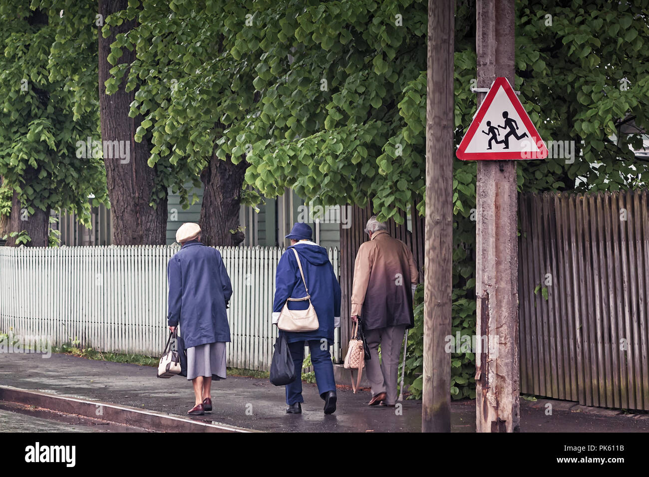 Drei Großmütter zu Fuß auf einer Straße an einem regnerischen Frühlingstag in Tallinn, der Hauptstadt Estlands. Die Verkehrszeichen vor Ihnen warnt vor laufenden Kind Stockfoto