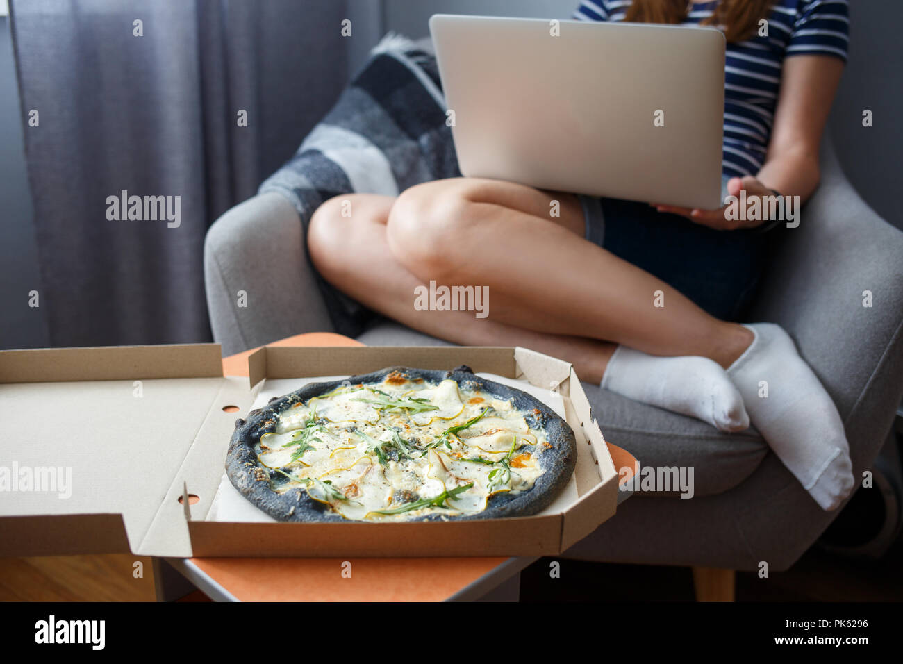 Junge Frau mit Laptop mit Pizza geliefert Stockfoto
