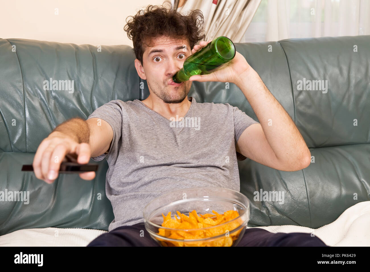 Ein junger Mann, der Fernsehen schaut und Änderungen tv beim Entspannen Stockfoto