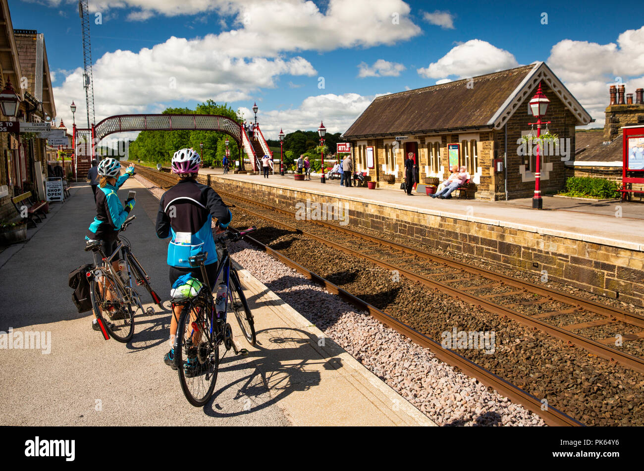 England, Yorkshire, vereinbaren, Radfahrer am Bahnhof Plattform warten auf Carlisle Railway Linie Zug vereinbaren Stockfoto