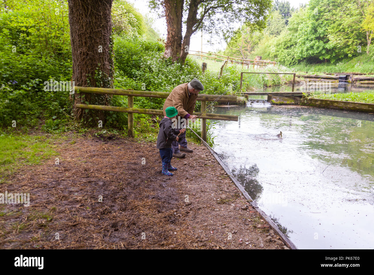 Vierjähriger Junge mit seinem Großvater in Meon Springs Trout Fishery, East Meon, Hampshire, England, Großbritannien. Stockfoto