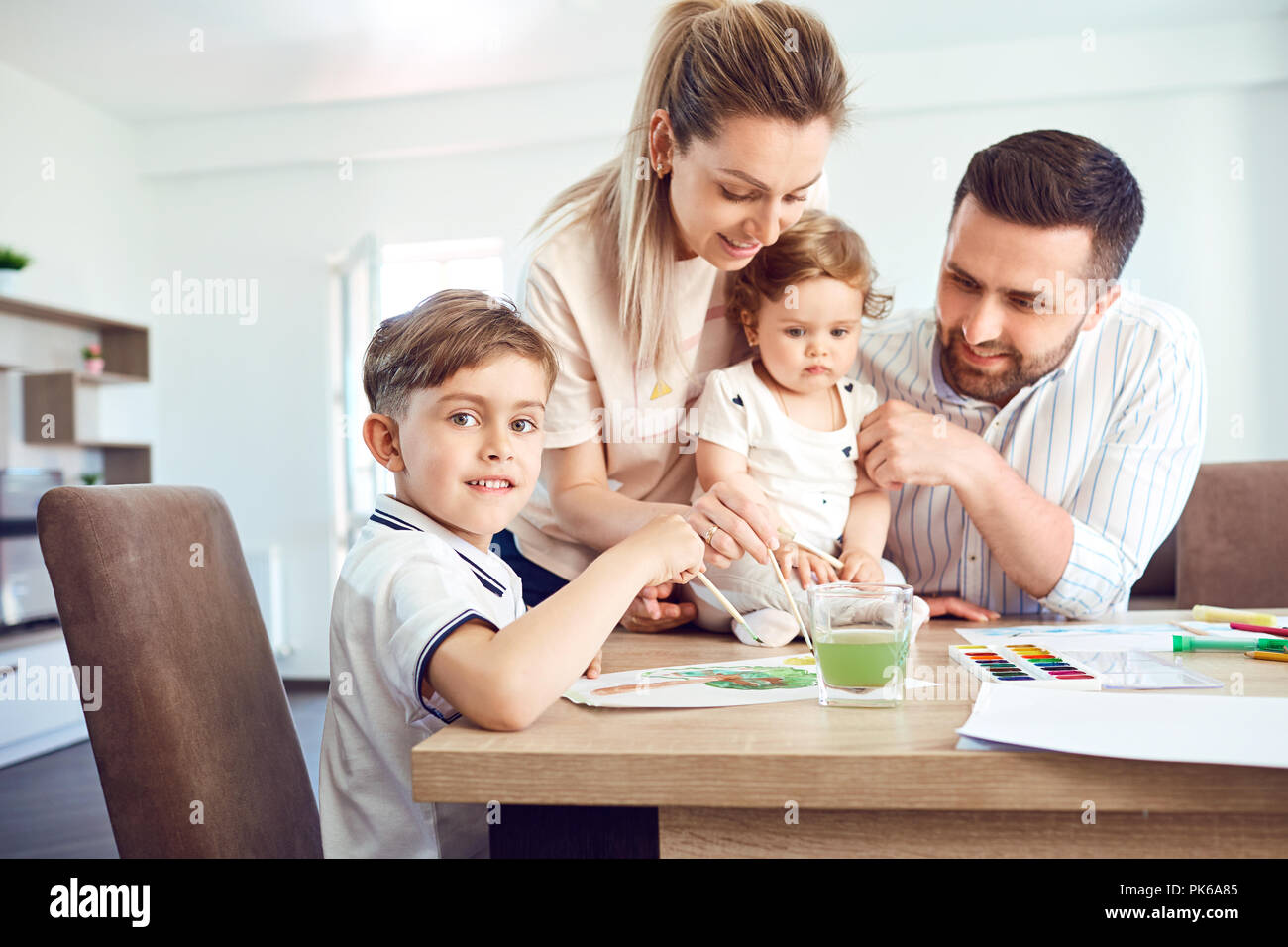 Glückliche Familie zieht malt auf ein Papier auf den Tisch. Stockfoto