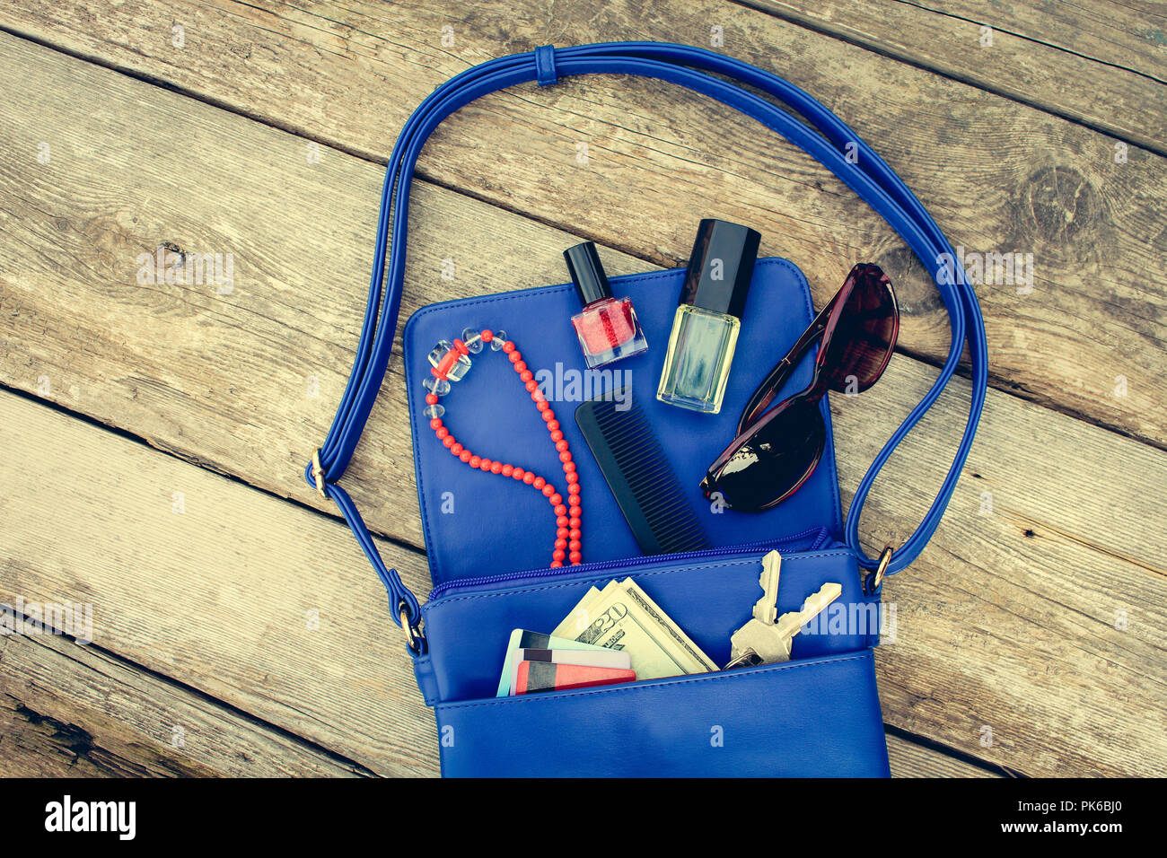 Dinge, die von den geöffneten Dame Handtasche. Kosmetika, Geld und Frauen Zubehör fiel aus blauen Handtasche. Ansicht von oben. Getönten Bild. Stockfoto