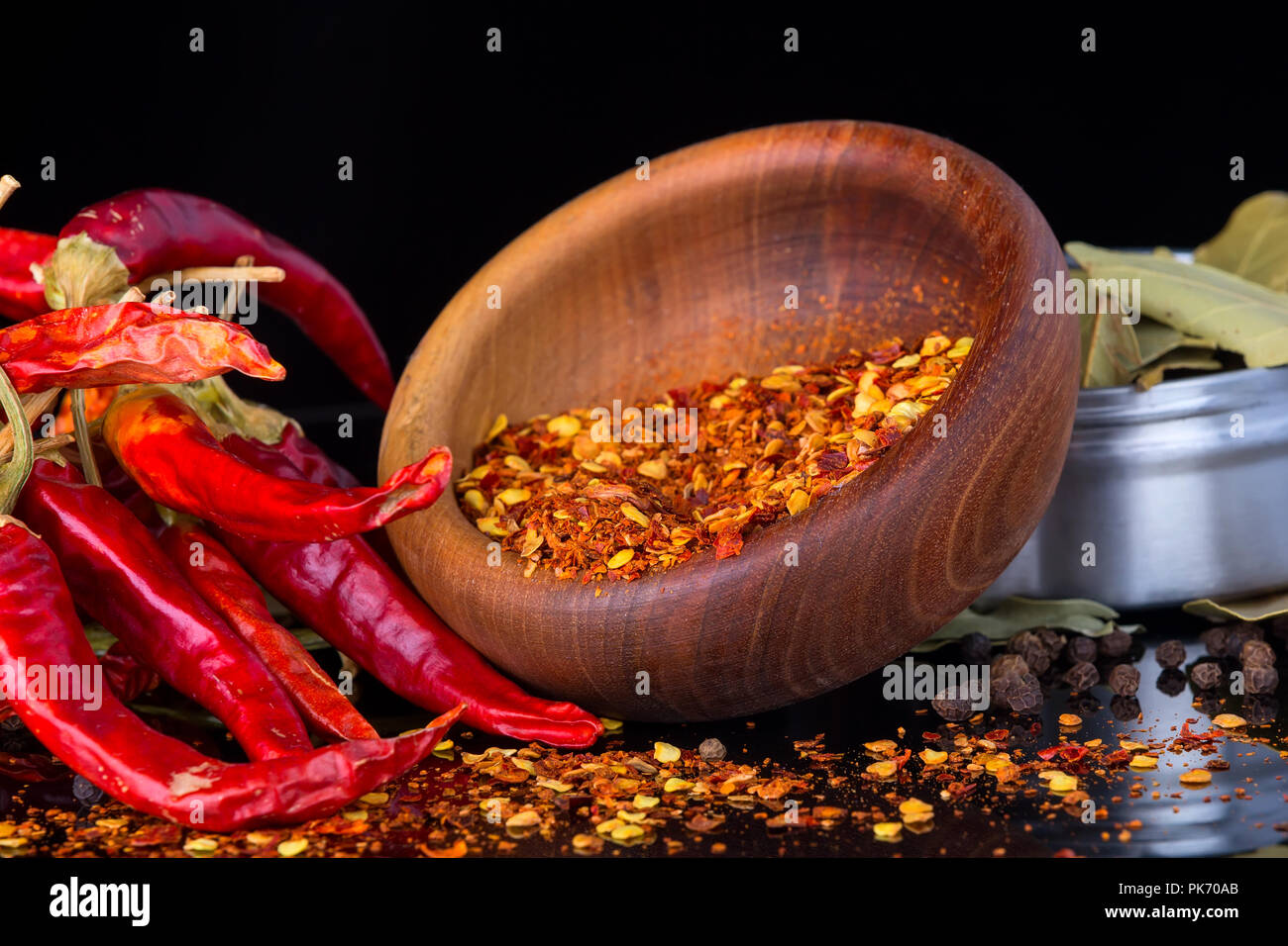 Rote Paprika und Chili Flocken auf einem schwarzen Hintergrund mit Reflektion Stockfoto