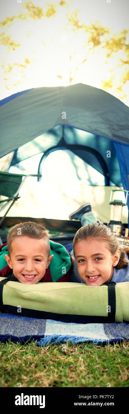 Lächelnd Geschwister außerhalb des Zeltes liegen Stockfoto