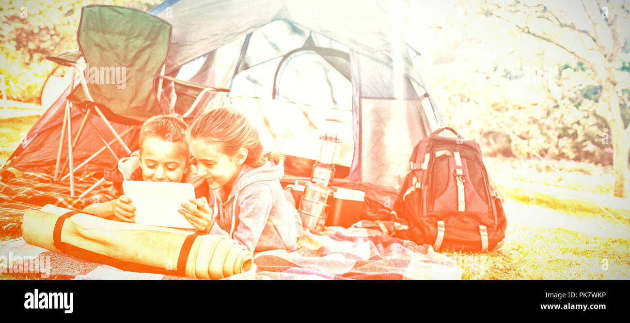 Geschwister mit Laptop außerhalb des Zeltes auf Campingplatz Stockfoto
