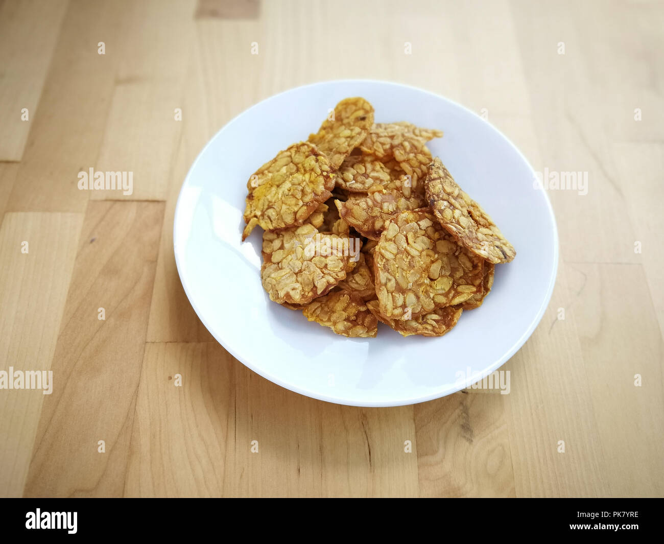 Gebratenen tempeh in einer weißen Platte auf der Holzoberfläche. Stockfoto