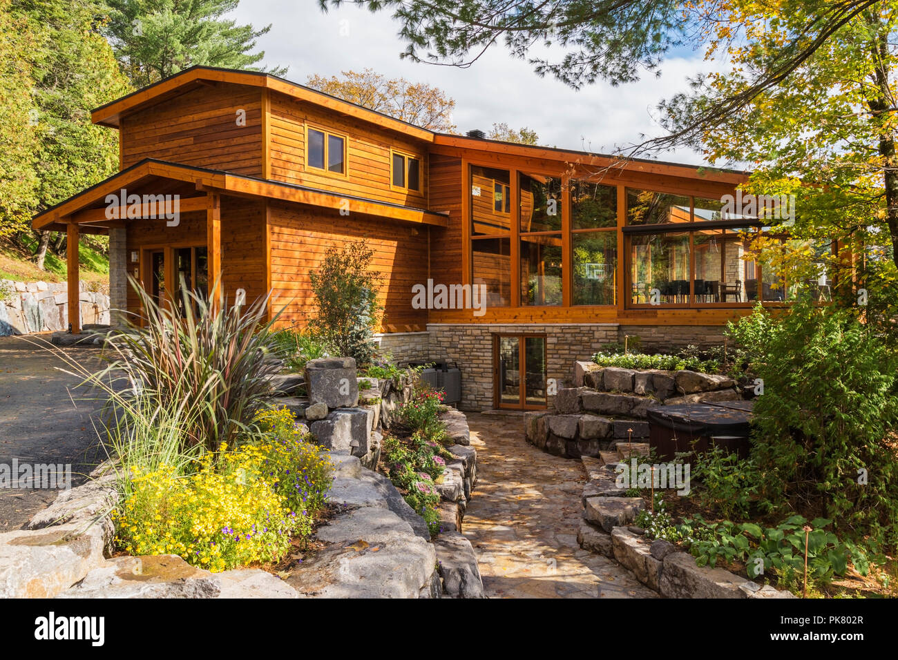 Luxuriöse gefärbt Zedern-und Holz Home mit Panoramafenstern und Landschaftsgestaltung im Herbst, Quebec, Kanada Stockfoto