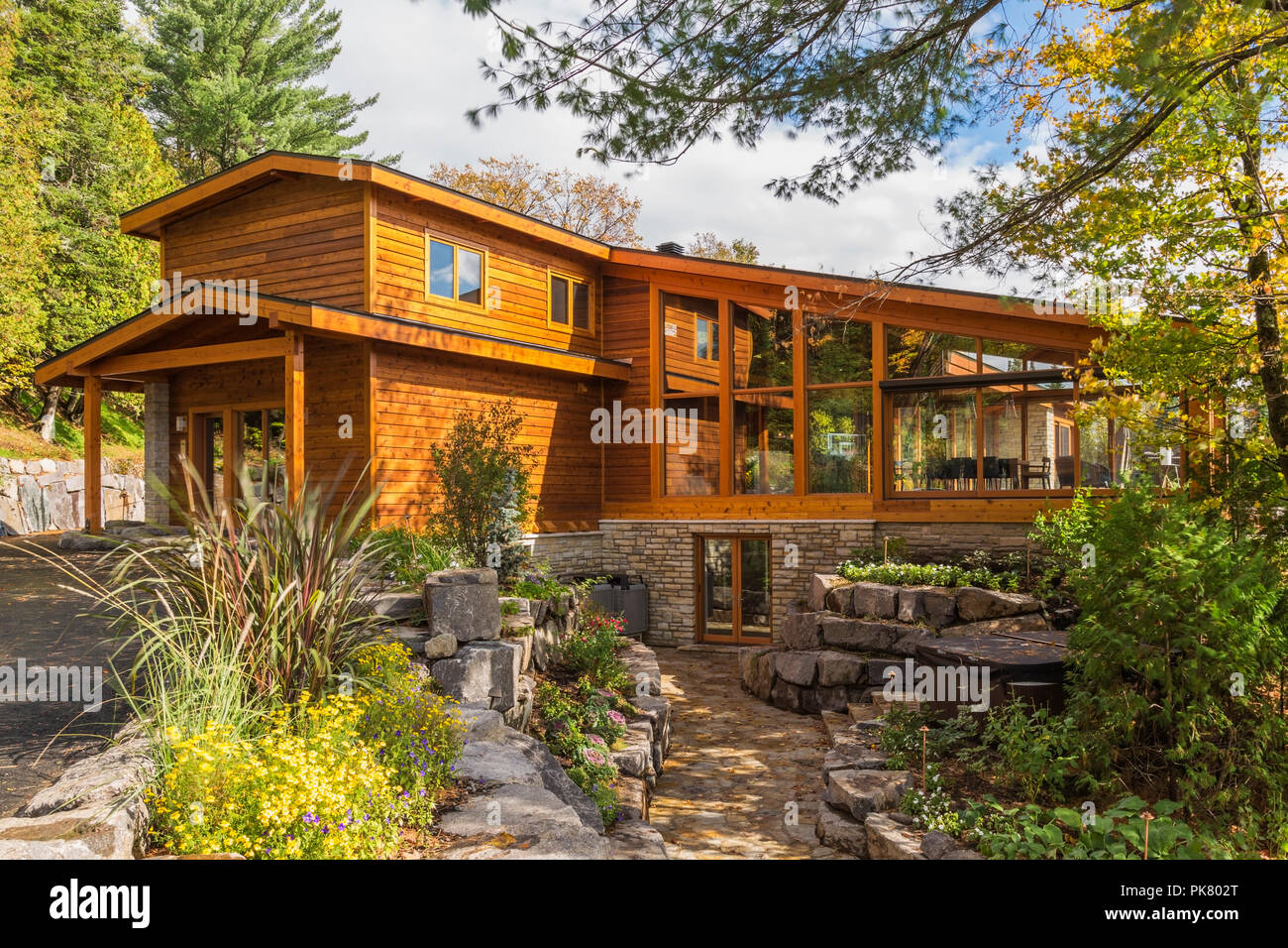 Luxuriöse Zedern-und Holz Home mit Panoramafenstern und Landschaftsgestaltung im Herbst, Quebec, Kanada Stockfoto