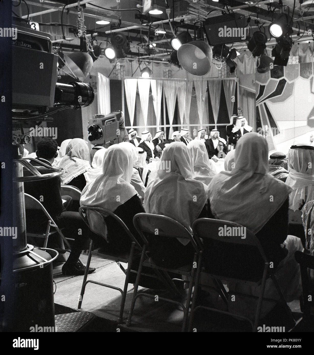 1960, historische, saudische Männer in traditionellen arabischen Kleid in eine komplett ausgestattete Vor sitzen - lit TV-Studio Abhören einer Debatte, die gefilmt werden, Saudi-Arabien. Stockfoto
