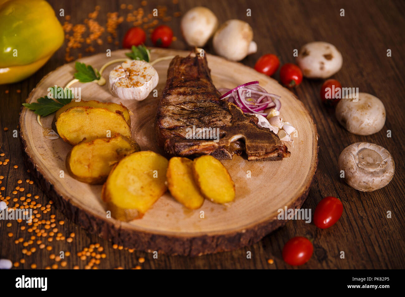 T Bone Steak Auf Einem Holzernen Substrat Und Gebackene Kartoffeln Neben Tomaten Knoblauch Gemuse Und Pilzen Stockfotografie Alamy