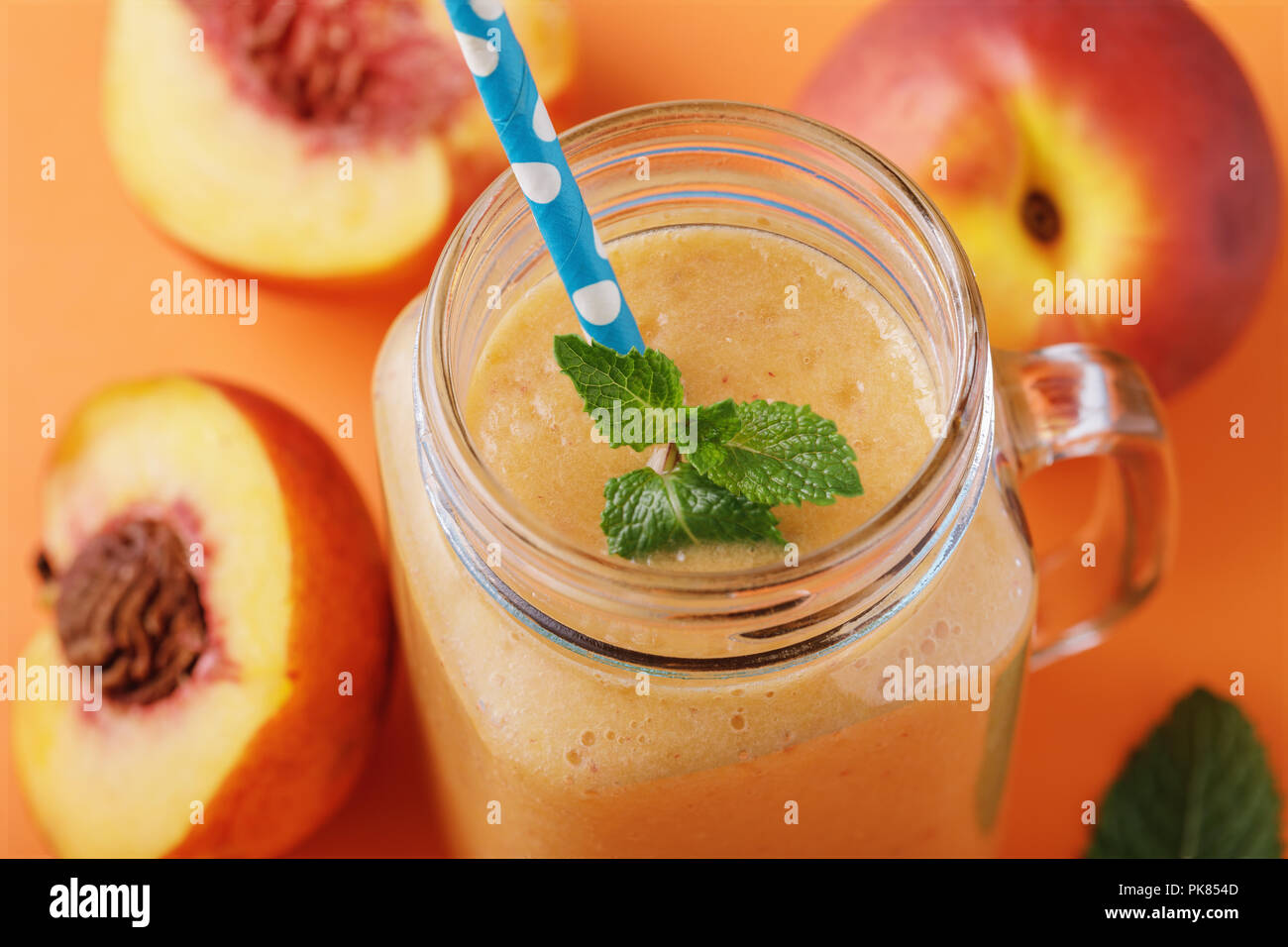 Smoothies von reife Pfirsiche im Glas mit Minze und Früchte auf einem Holztisch, close-up Stockfoto