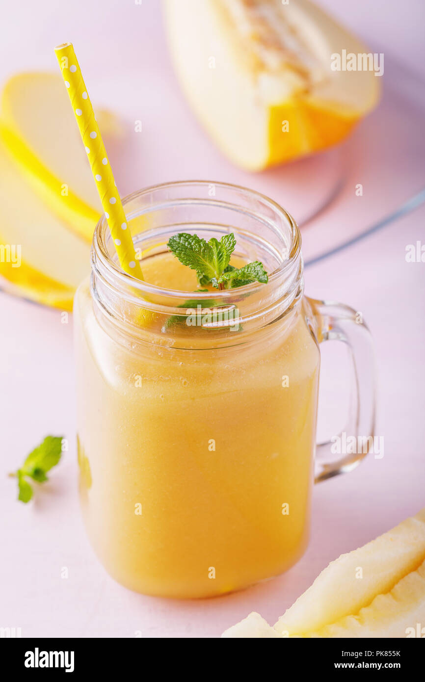 Smoothies aus reifen Melone in einem Glas mit Minze und Früchte auf einem hölzernen Tisch zubereitet Stockfoto