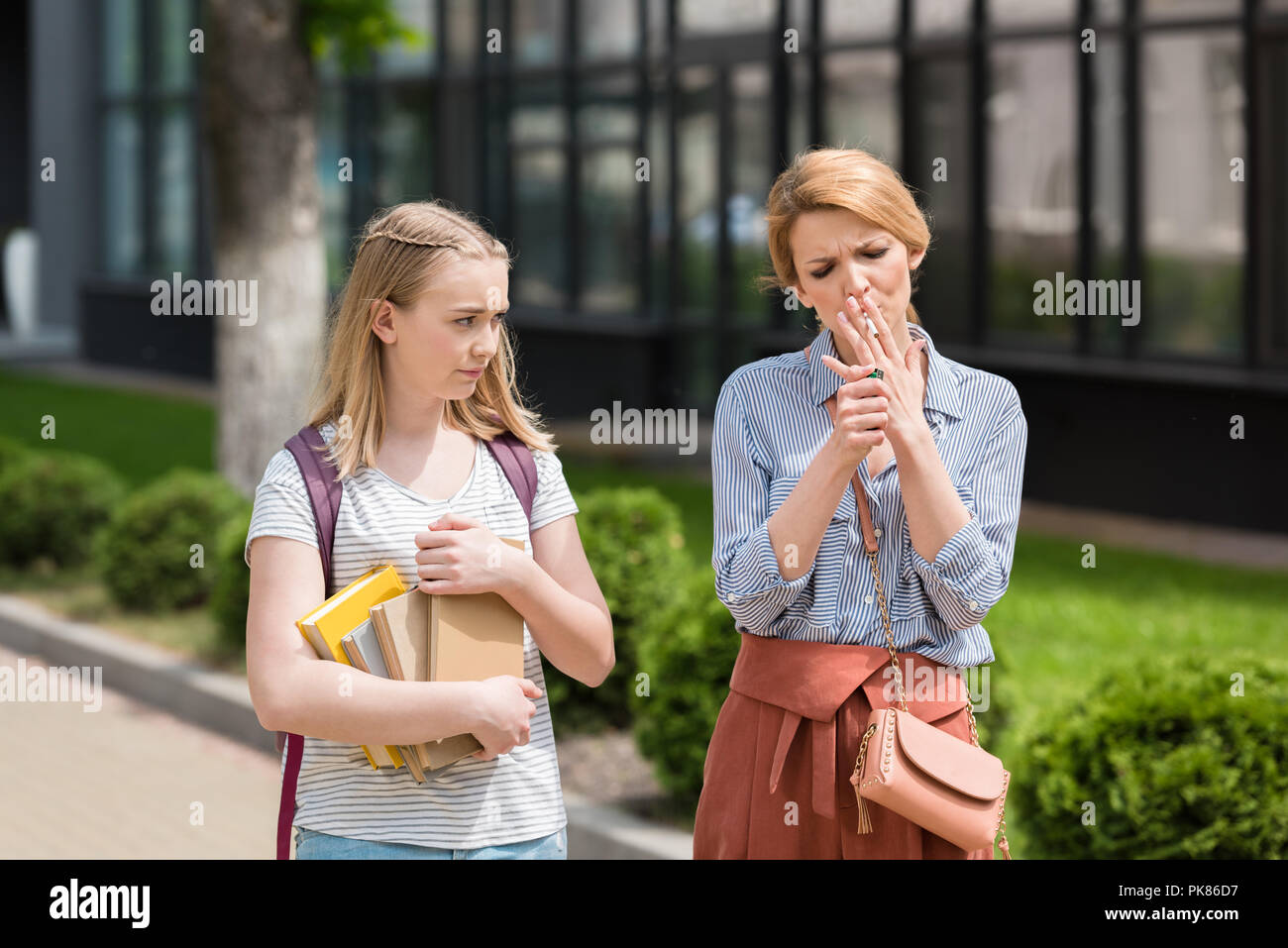 Angewidert jugendlich Tochter, Mutter, während das Rauchen von Zigaretten Stockfoto