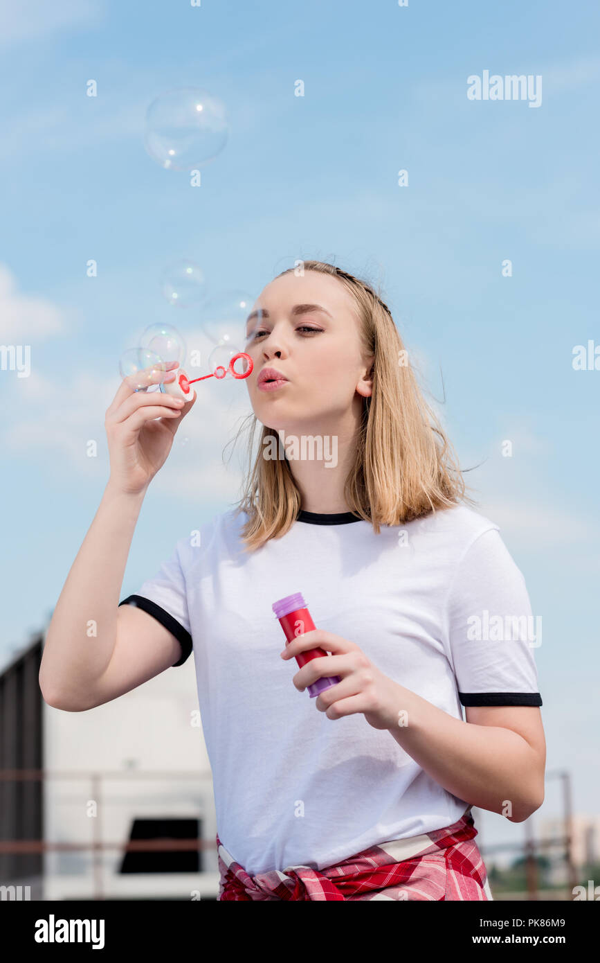 Schöne jugendlich Mädchen bläst Seifenblasen vor blauem Himmel Stockfoto