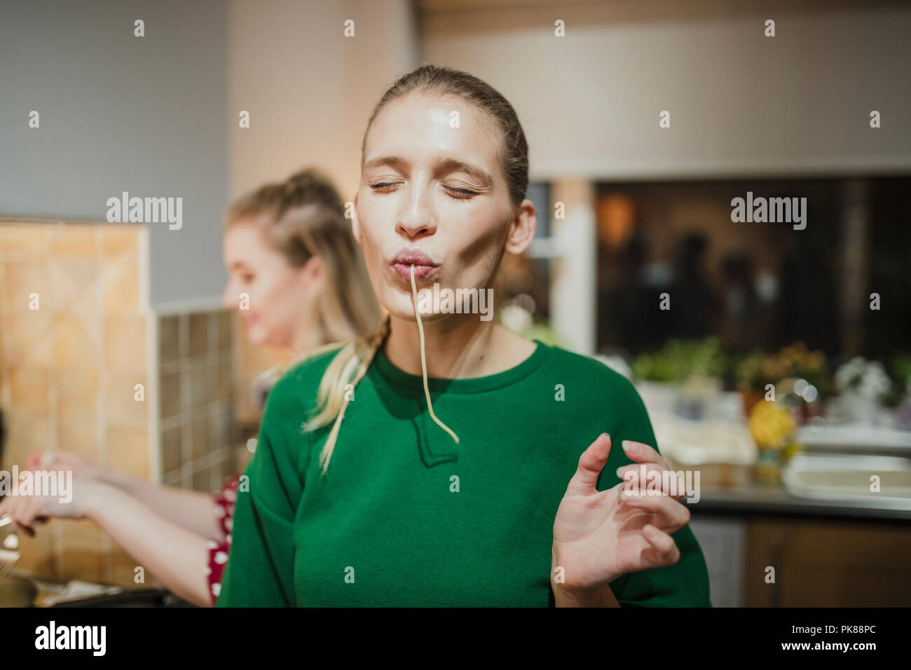 Junge Frau posiert für die Kamera mit Spaghetti hängen ihren Mund. Stockfoto
