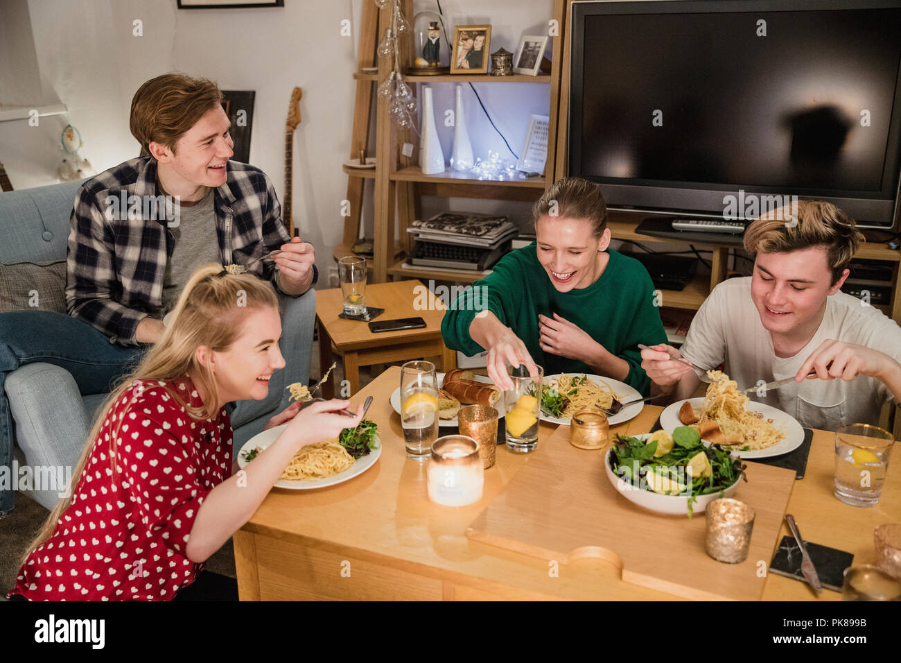 Zwei junge Paare sind, genießen Sie ein Dinner Party zu Hause. Sie essen hausgemachte Spaghetti Carbonara mit Knoblauchbrot und Salat. Stockfoto