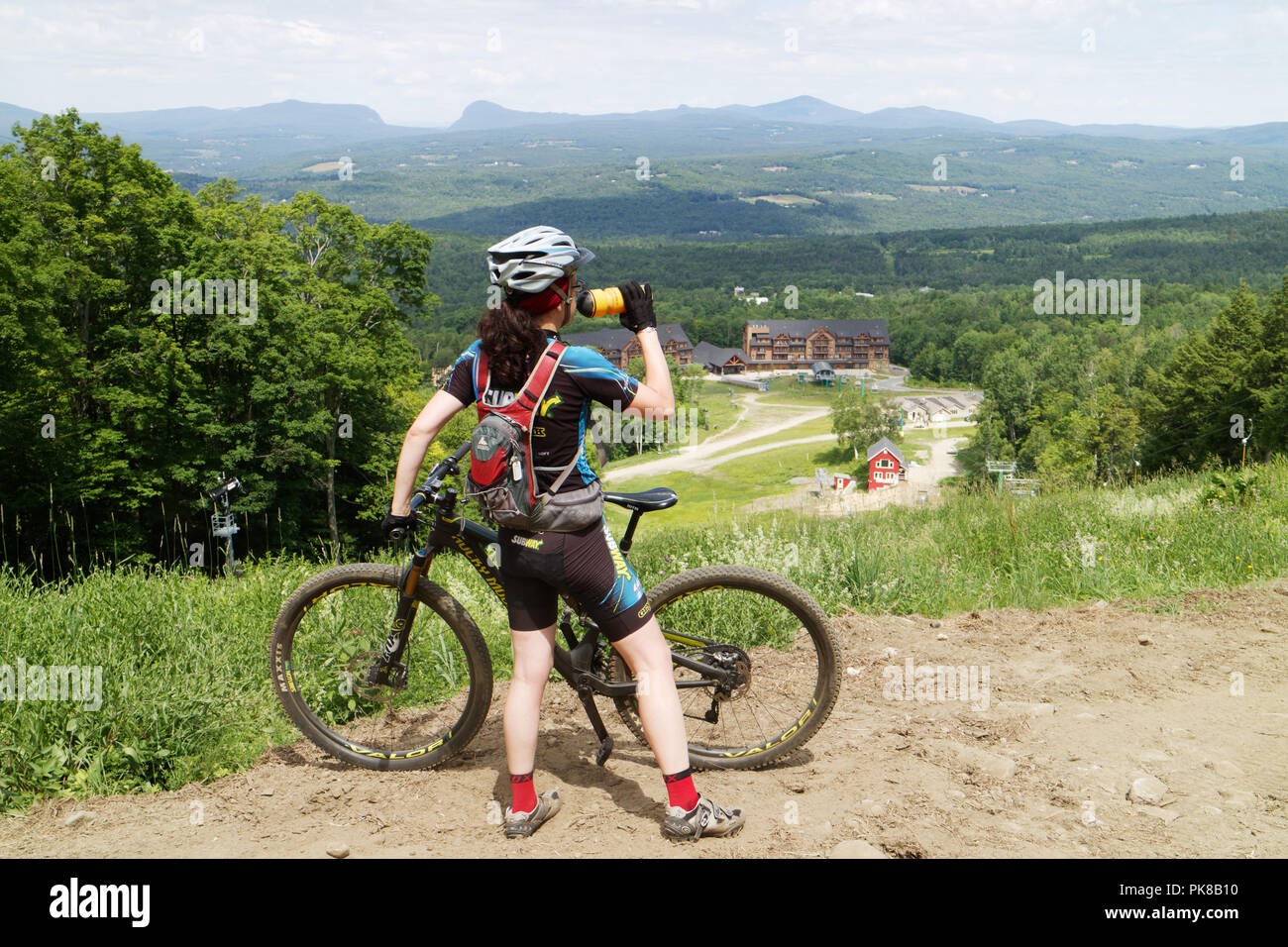 Eine Dame Mountainbiker (in ihrem 40s) Pausen Wasser auf das Königreich Trails mountain bike Park im Osten Burke, Vermont, USA zu trinken Stockfoto
