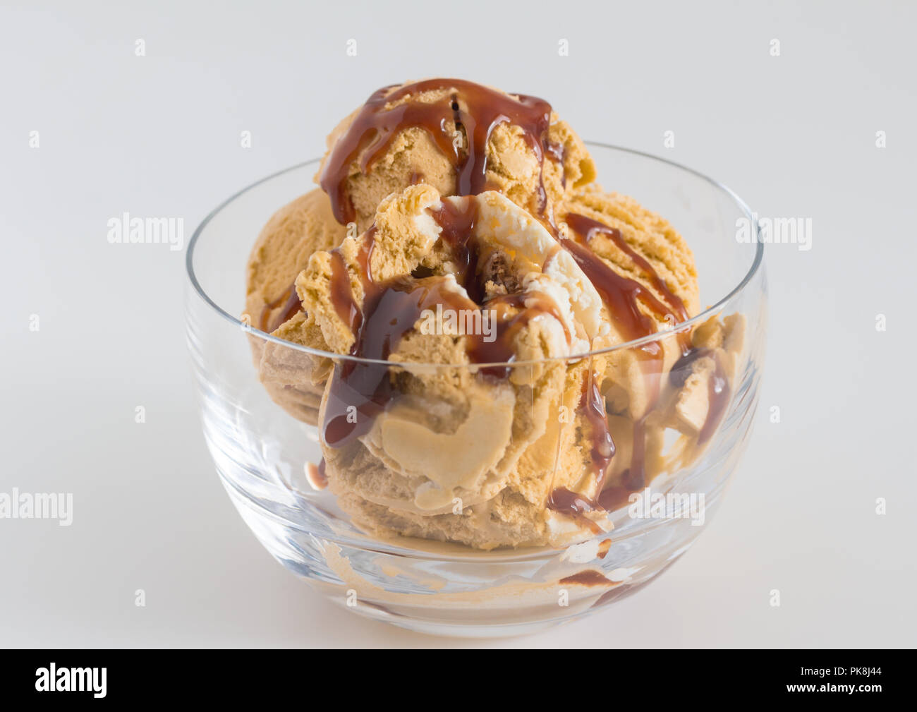 Eis in Glasschale - Caramel und Vanille Eis beträufelt mit Schokolade Sirup hautnah. Stockfoto