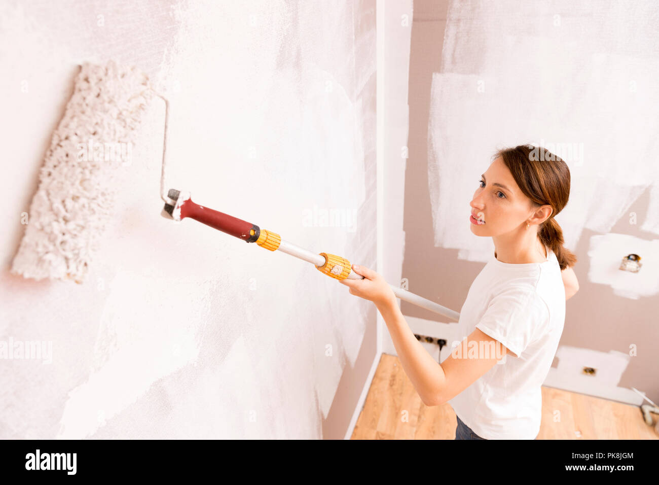 Home Improvement. Schöne Frau Malerei Wand mit Farbroller. Stockfoto