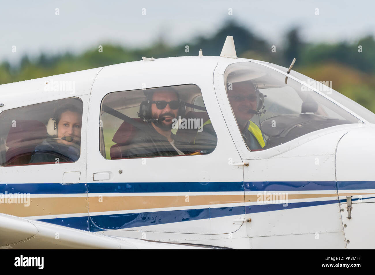 Kleine Gruppe von Menschen sitzen in einem Motor der privaten Flugzeuge, die man vom Fenster aus sieht lächelnd, bereit, in Großbritannien. Private Pilot. Stockfoto