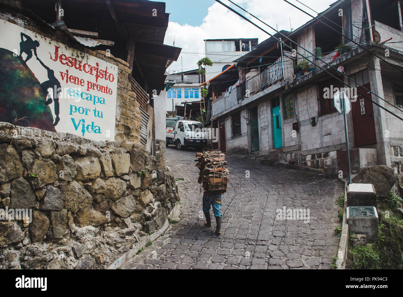 Arbeiter trägt schwere Last von Holz auf dem Rücken auf einem Hügel in Guatemala, vorbei an einem Schild mit der Aufschrift: "Jesus Christus kommt bald, durch dein Leben Escape' Stockfoto